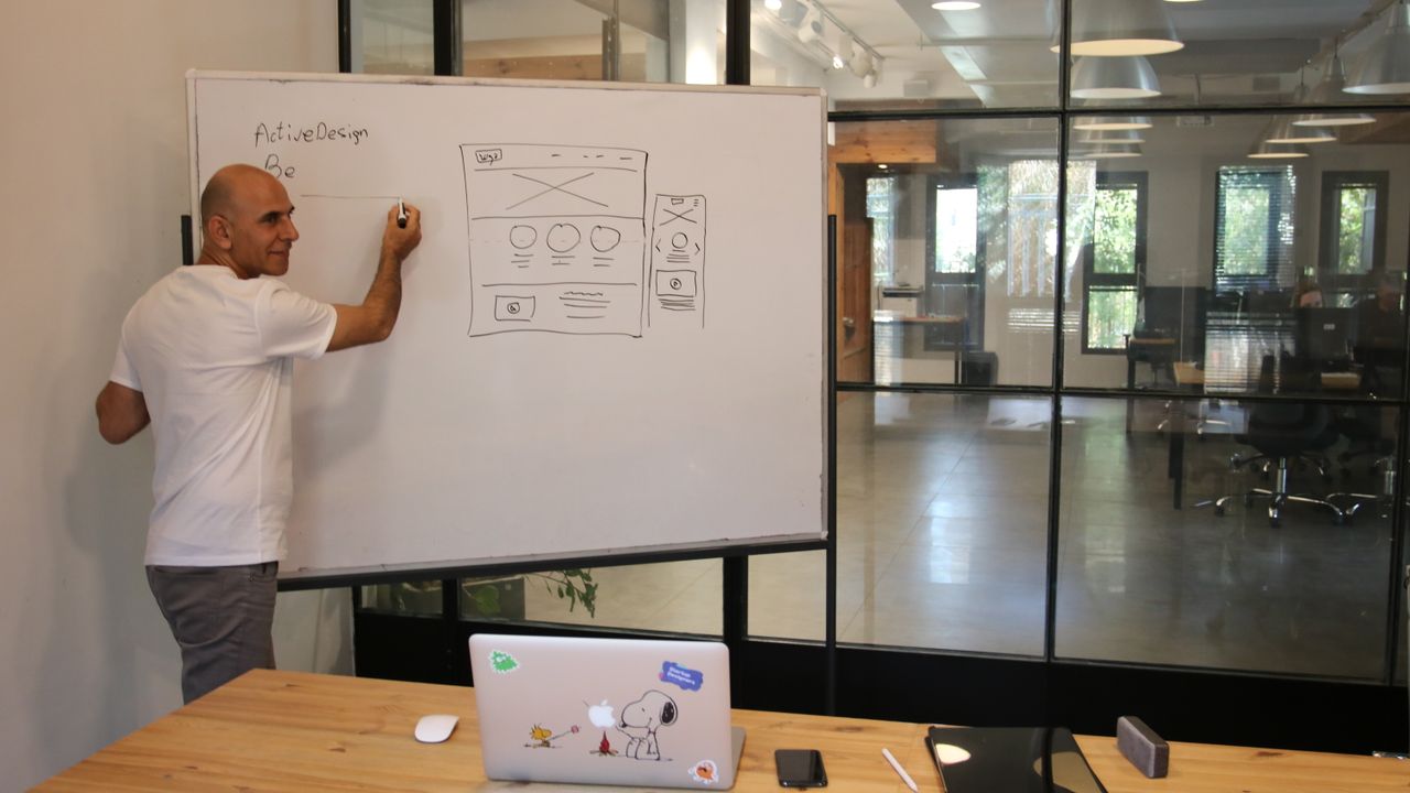 A designer drawing a website wireframe on a whiteboard in an office