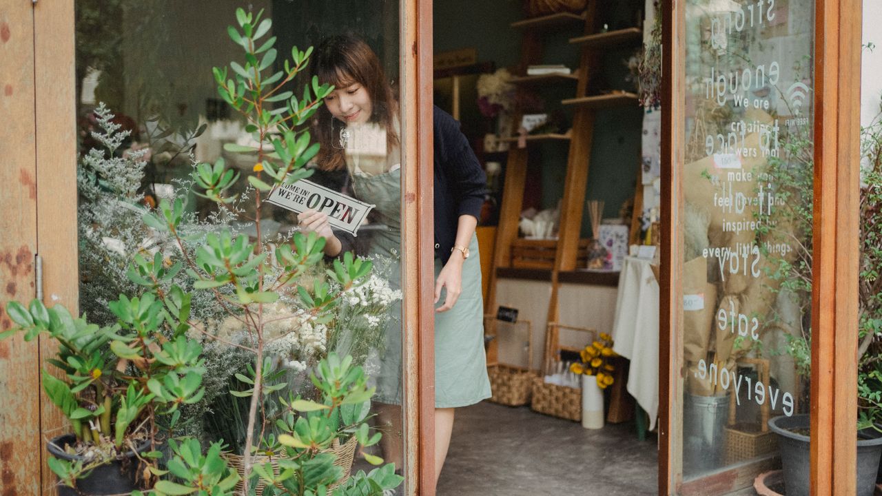 A small business owner turning the open sign in their shop window