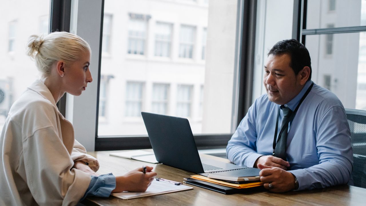 A hiring manager interviewing a candidate across a desk, the step a vetting network like Toptal does before a company meets anyone