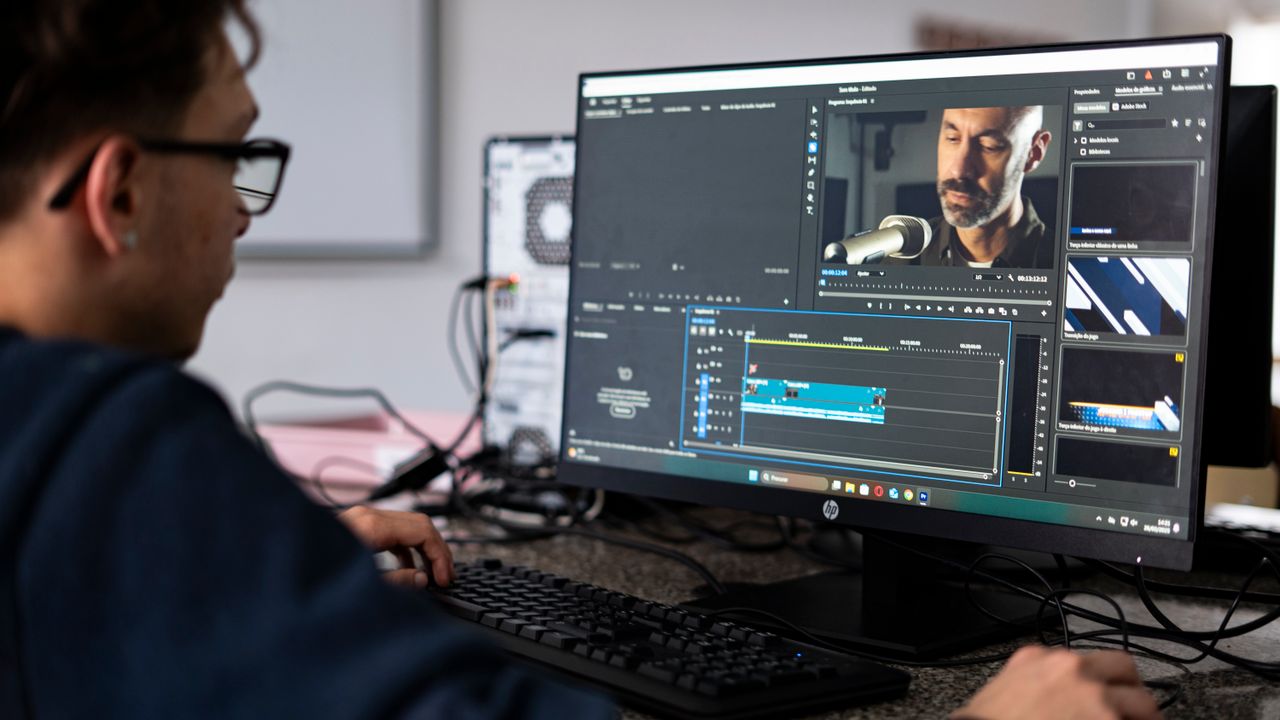 A video editor reviewing YouTube ad footage on a desktop computer in an office